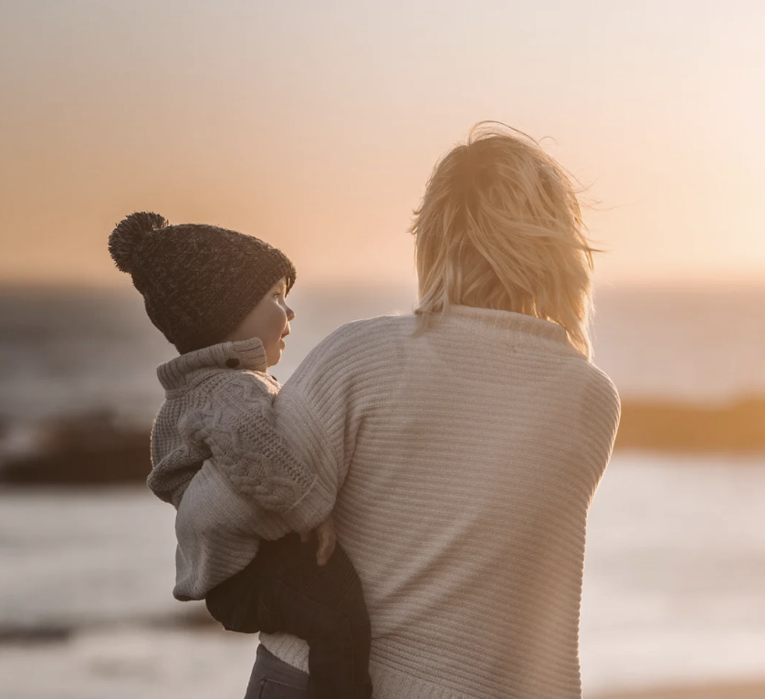 Parent holding a young child at sunset